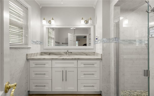 bathroom with walk in shower, vanity, tile walls, and ornamental molding