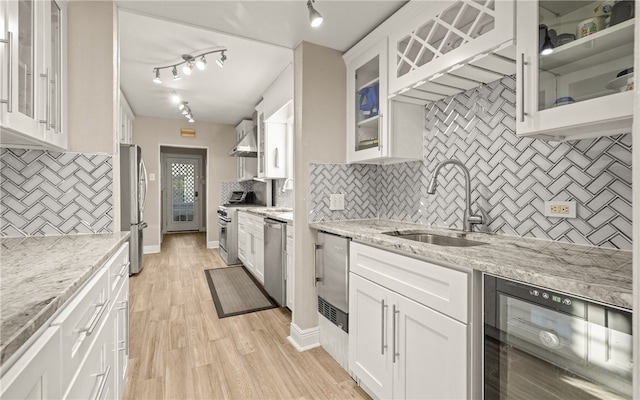 kitchen with tasteful backsplash, wine cooler, white cabinetry, and light wood-type flooring