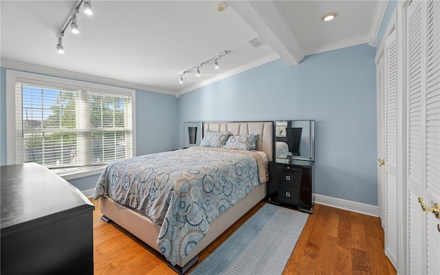 bedroom with crown molding, light hardwood / wood-style flooring, beamed ceiling, and rail lighting