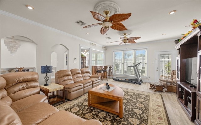 living room with ceiling fan with notable chandelier, light hardwood / wood-style flooring, and ornamental molding