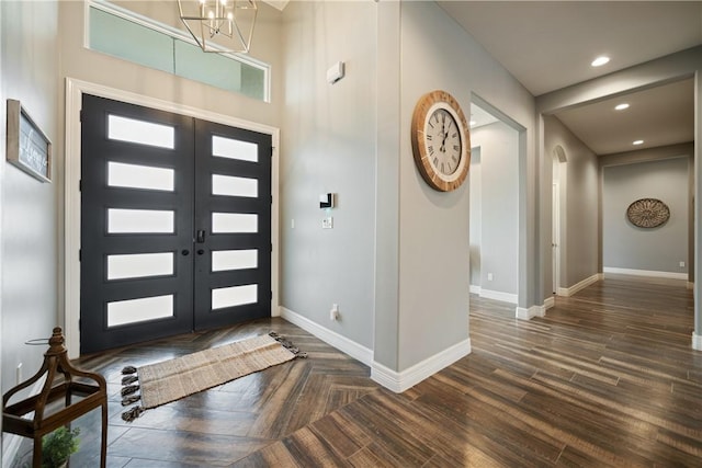 foyer entrance with an inviting chandelier, dark wood-type flooring, and french doors