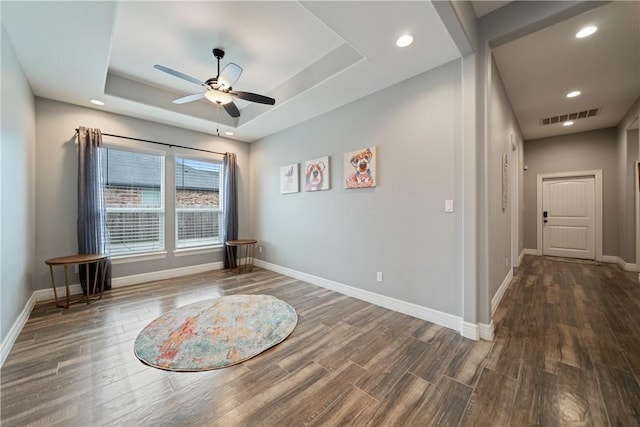 unfurnished room featuring a raised ceiling and ceiling fan