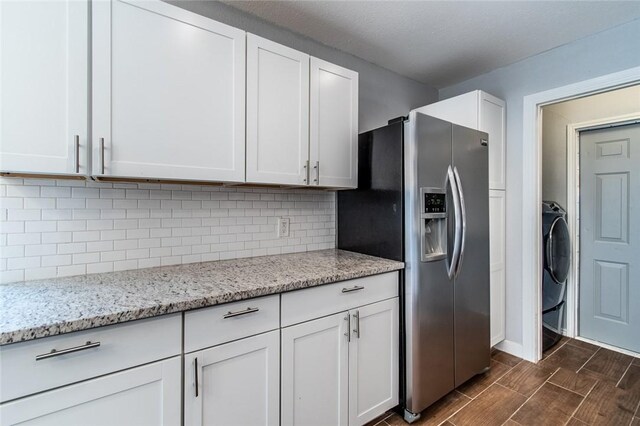 kitchen with white cabinetry, light stone countertops, stainless steel fridge, and tasteful backsplash