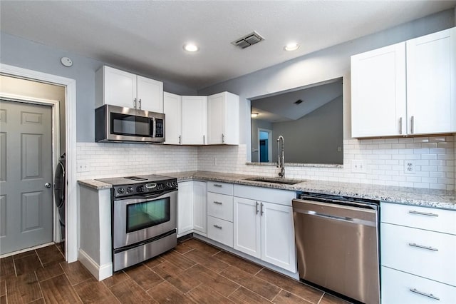 kitchen with light stone countertops, appliances with stainless steel finishes, a sink, white cabinetry, and visible vents