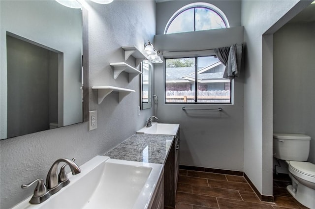 full bathroom featuring a sink, wood tiled floor, baseboards, and toilet