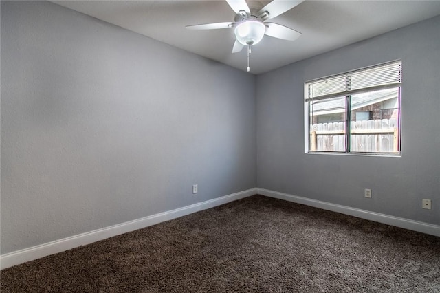 spare room featuring dark colored carpet, baseboards, and ceiling fan
