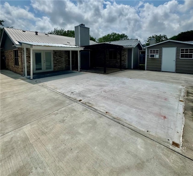 view of patio featuring a storage unit, an outbuilding, and french doors