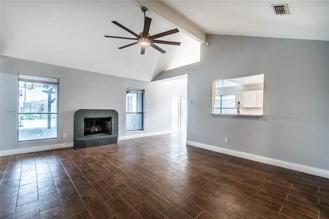 unfurnished living room with visible vents, a brick fireplace, beamed ceiling, baseboards, and a ceiling fan