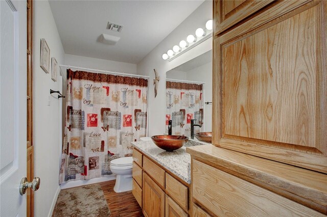 bathroom with curtained shower, vanity, hardwood / wood-style flooring, and toilet