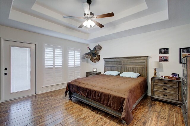 bedroom with a tray ceiling, hardwood / wood-style flooring, and ceiling fan