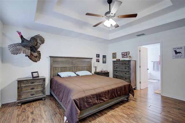 bedroom featuring wood-type flooring, ceiling fan, and a tray ceiling