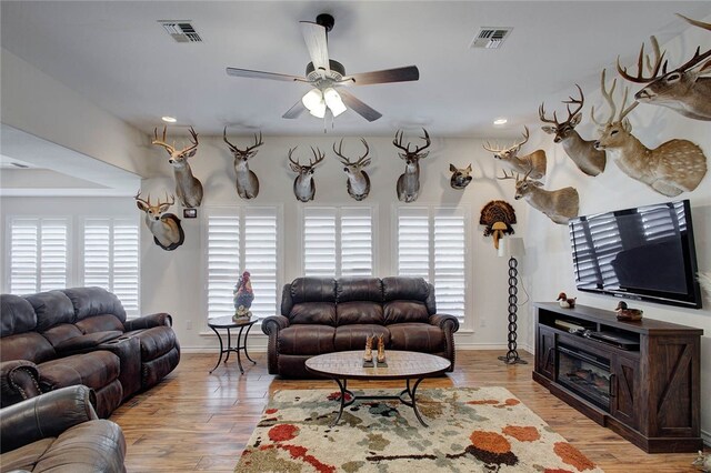 living room with light wood-type flooring, a fireplace, and ceiling fan