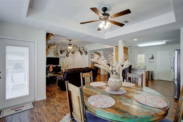 dining room featuring ceiling fan, a tray ceiling, and dark hardwood / wood-style floors