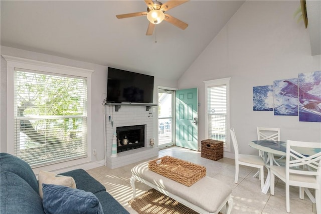 living area featuring light tile patterned floors, high vaulted ceiling, a brick fireplace, and ceiling fan