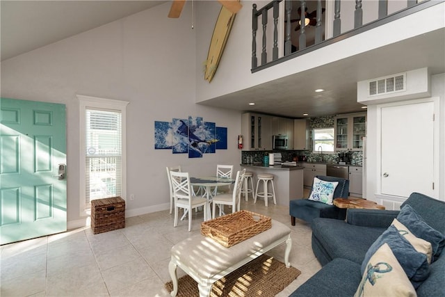 living room with light tile patterned floors, visible vents, high vaulted ceiling, and a ceiling fan
