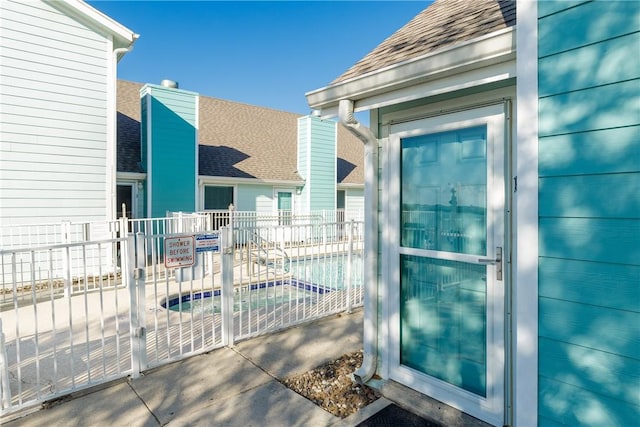 doorway to property with roof with shingles