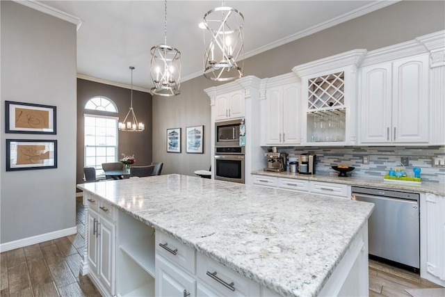 kitchen featuring appliances with stainless steel finishes, a kitchen island, white cabinetry, a chandelier, and hanging light fixtures