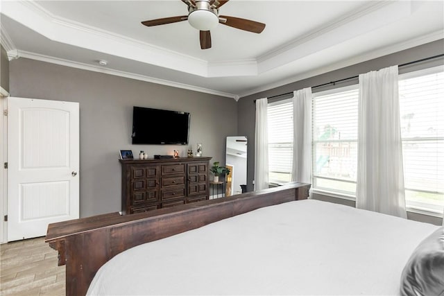 bedroom with crown molding, a raised ceiling, ceiling fan, and light wood-type flooring