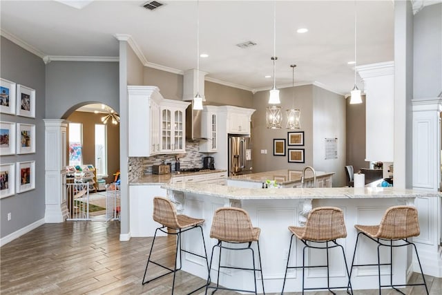 kitchen with a breakfast bar, backsplash, hanging light fixtures, light stone countertops, and a spacious island