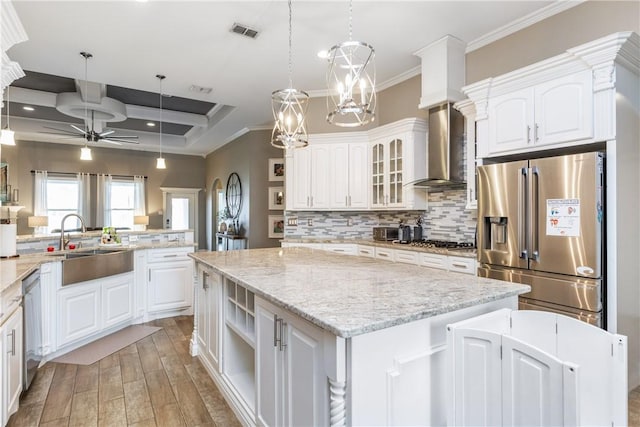 kitchen featuring appliances with stainless steel finishes, wall chimney range hood, a kitchen island, and white cabinets