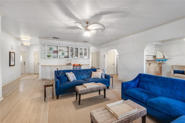 living room with ceiling fan, light wood-type flooring, and crown molding