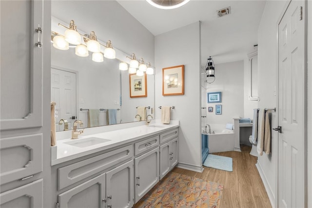 bathroom with vanity, hardwood / wood-style flooring, and a tub to relax in