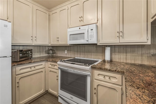 kitchen featuring dark stone countertops, white appliances, cream cabinets, and dark hardwood / wood-style floors