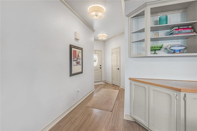 corridor with light wood-type flooring and crown molding