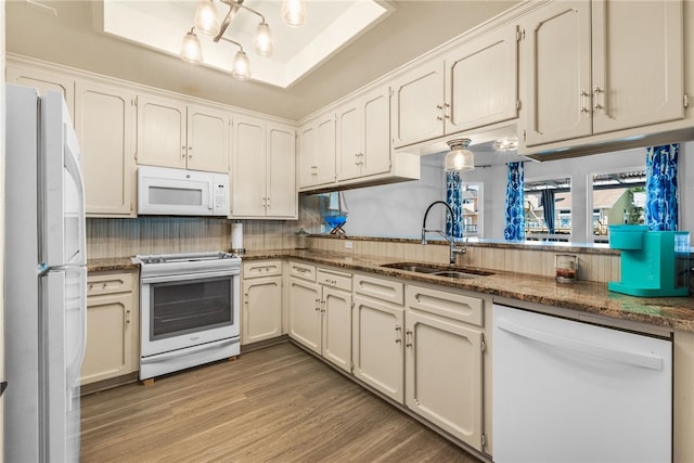 kitchen featuring light hardwood / wood-style floors, sink, dark stone countertops, backsplash, and white appliances