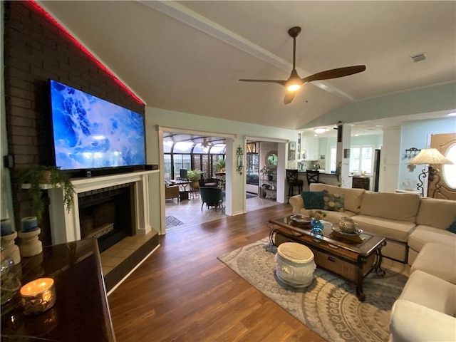 living area with a ceiling fan, plenty of natural light, wood finished floors, and vaulted ceiling