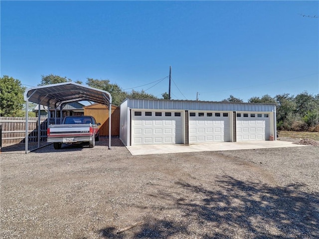 detached garage featuring a carport and fence