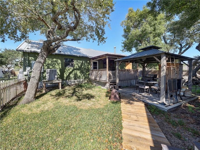 rear view of house with fence, a deck, a gazebo, and a lawn