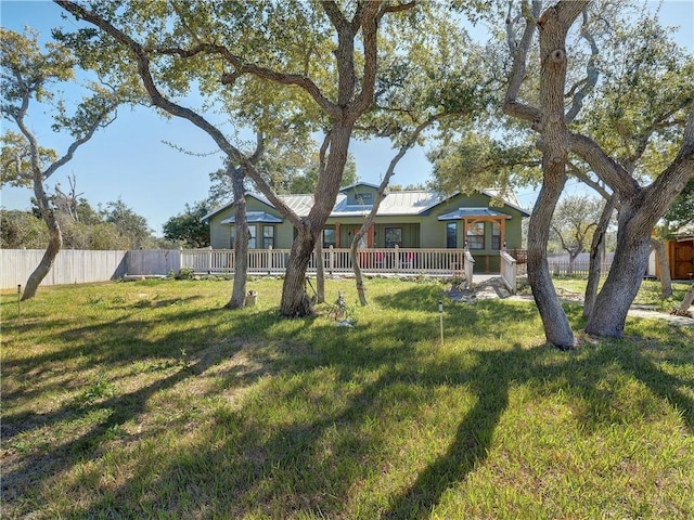 view of front of house featuring metal roof, a front yard, and fence