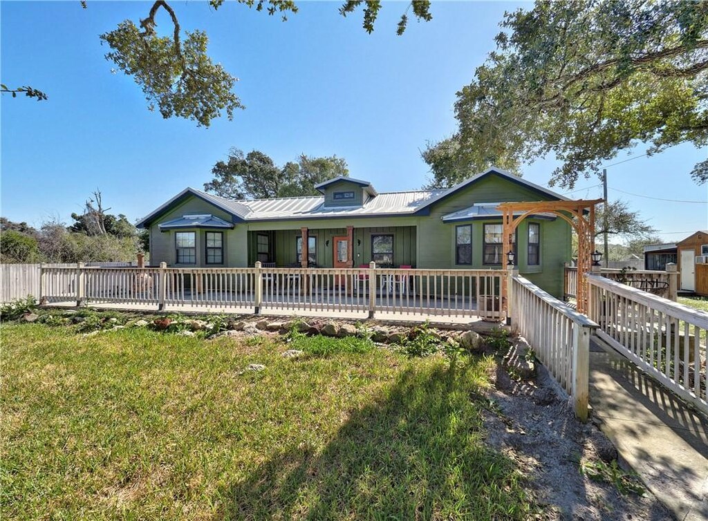 1045 N Mccampbell, Aransas Pass, TX 78336 - view of front of home with metal roof, a front yard, and fence