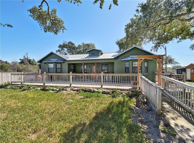 view of front of home with metal roof, a front yard, and fence