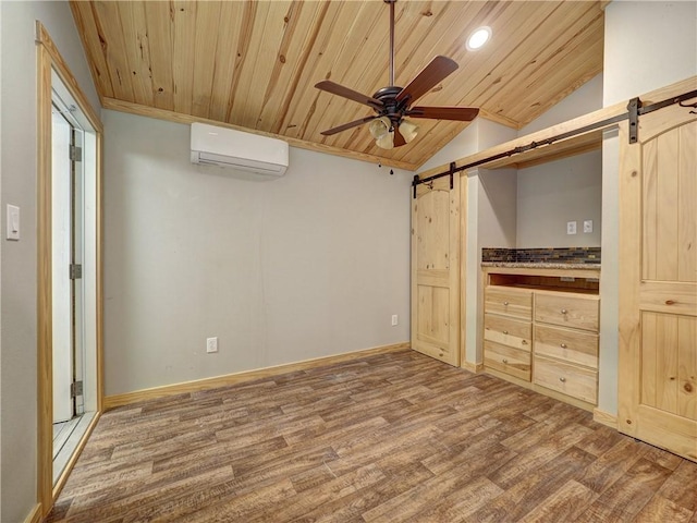 unfurnished bedroom featuring wood finished floors, wooden ceiling, a wall unit AC, and a barn door