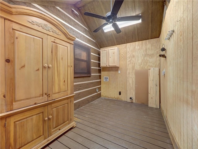 interior space featuring lofted ceiling with beams, wood walls, light wood finished floors, and a ceiling fan