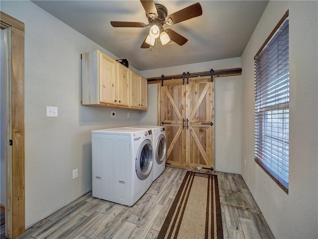 laundry area with cabinet space, a barn door, a ceiling fan, wood tiled floor, and separate washer and dryer