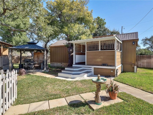 view of front facade featuring metal roof, a gazebo, a front yard, and an outdoor structure