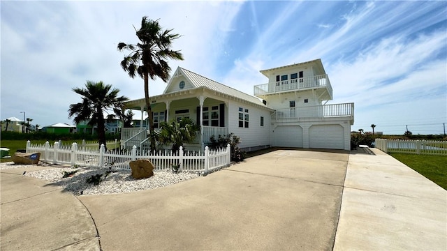 view of front of house featuring a balcony, a fenced front yard, and concrete driveway