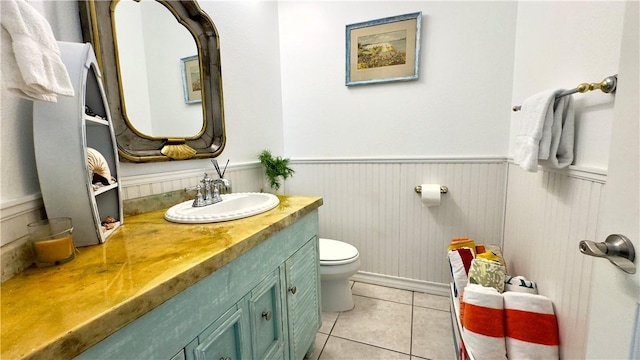 bathroom with vanity, wainscoting, tile patterned flooring, and toilet