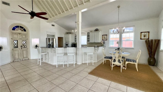 dining room with light tile patterned floors, visible vents, high vaulted ceiling, beamed ceiling, and ceiling fan with notable chandelier