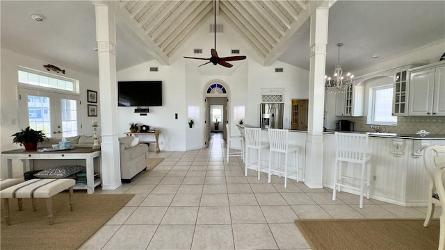 kitchen with glass insert cabinets, open floor plan, decorative light fixtures, stainless steel refrigerator with ice dispenser, and light tile patterned flooring