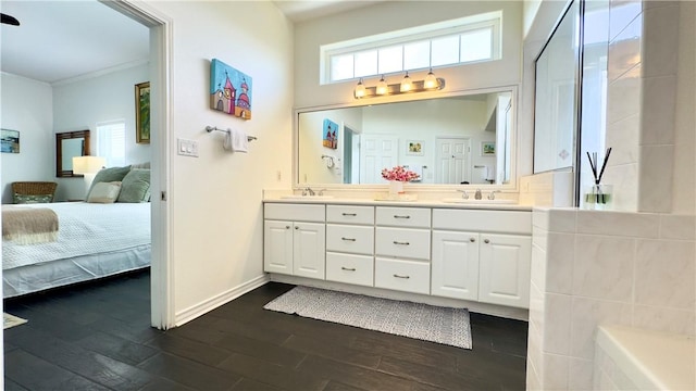 bathroom with double vanity, connected bathroom, a sink, wood finished floors, and baseboards