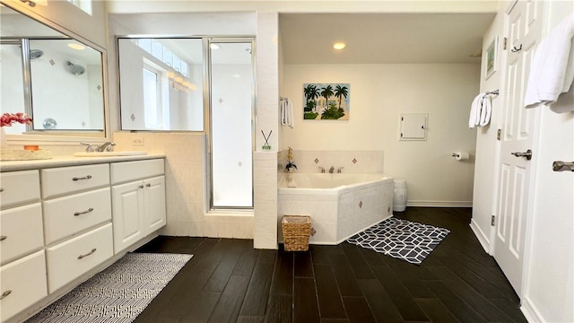 full bath with a garden tub, wood finished floors, vanity, baseboards, and a shower stall