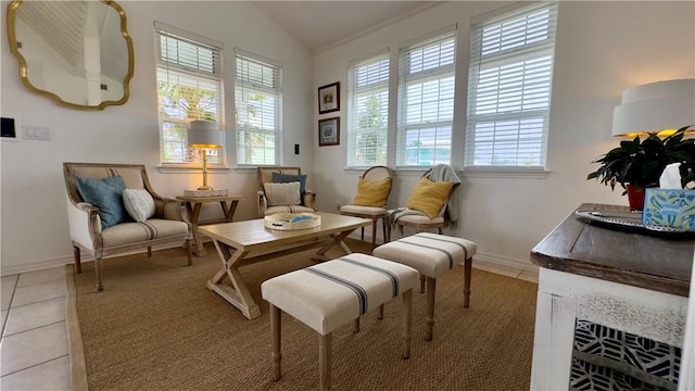 living area featuring light tile patterned floors, vaulted ceiling, and baseboards