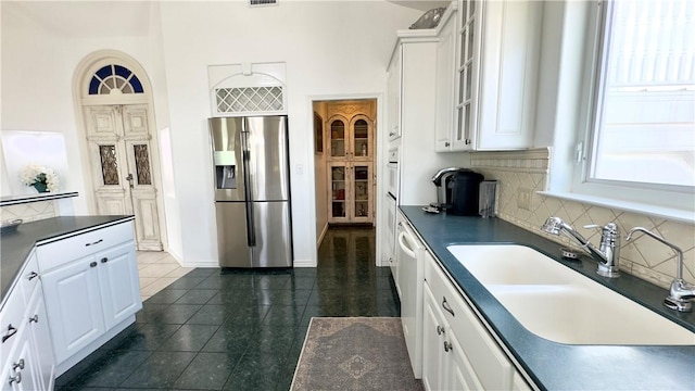 kitchen with dark countertops, white cabinetry, a sink, and stainless steel fridge with ice dispenser