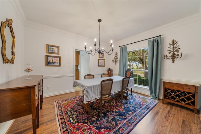 dining room with hardwood / wood-style flooring, ornamental molding, and an inviting chandelier