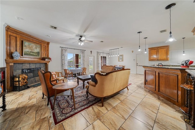 living room featuring ceiling fan and a tile fireplace