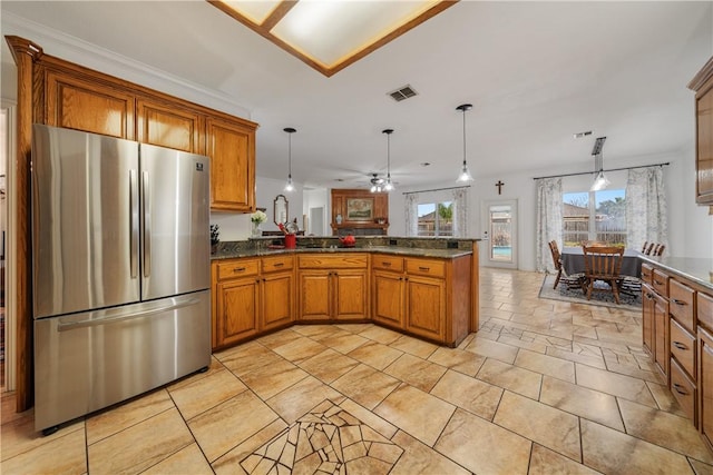 kitchen featuring hanging light fixtures, stainless steel fridge, kitchen peninsula, and dark stone countertops